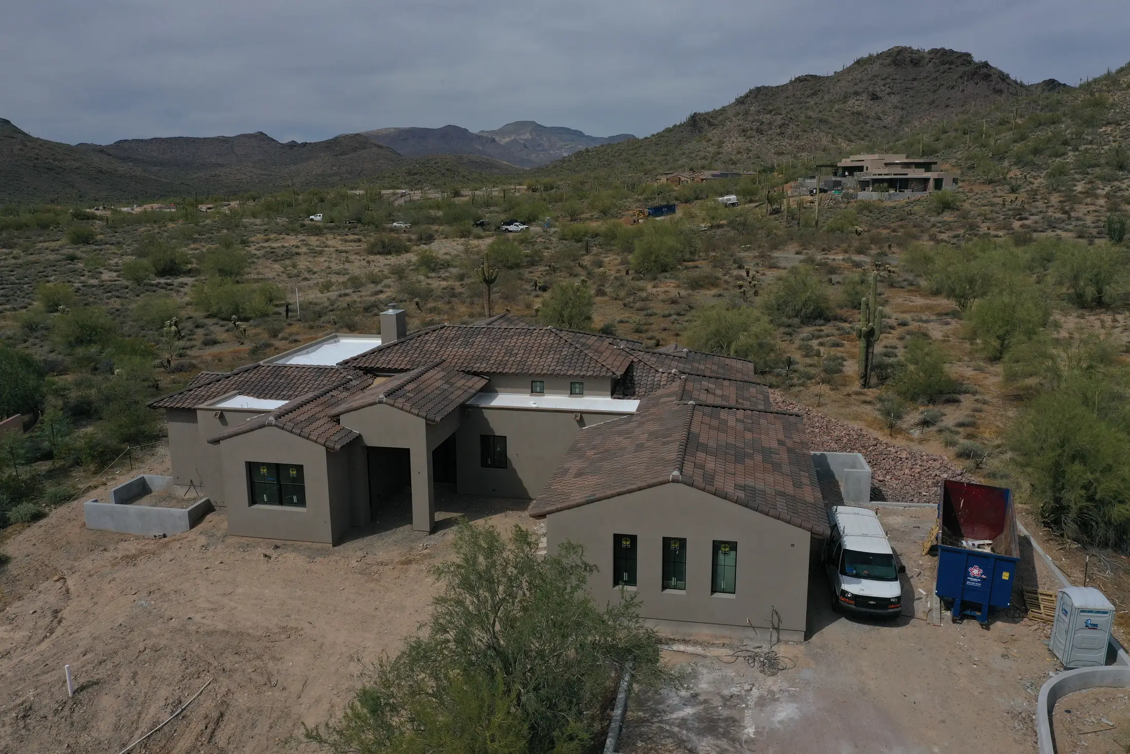 Drone view of a tile-roofed desert home during roof work