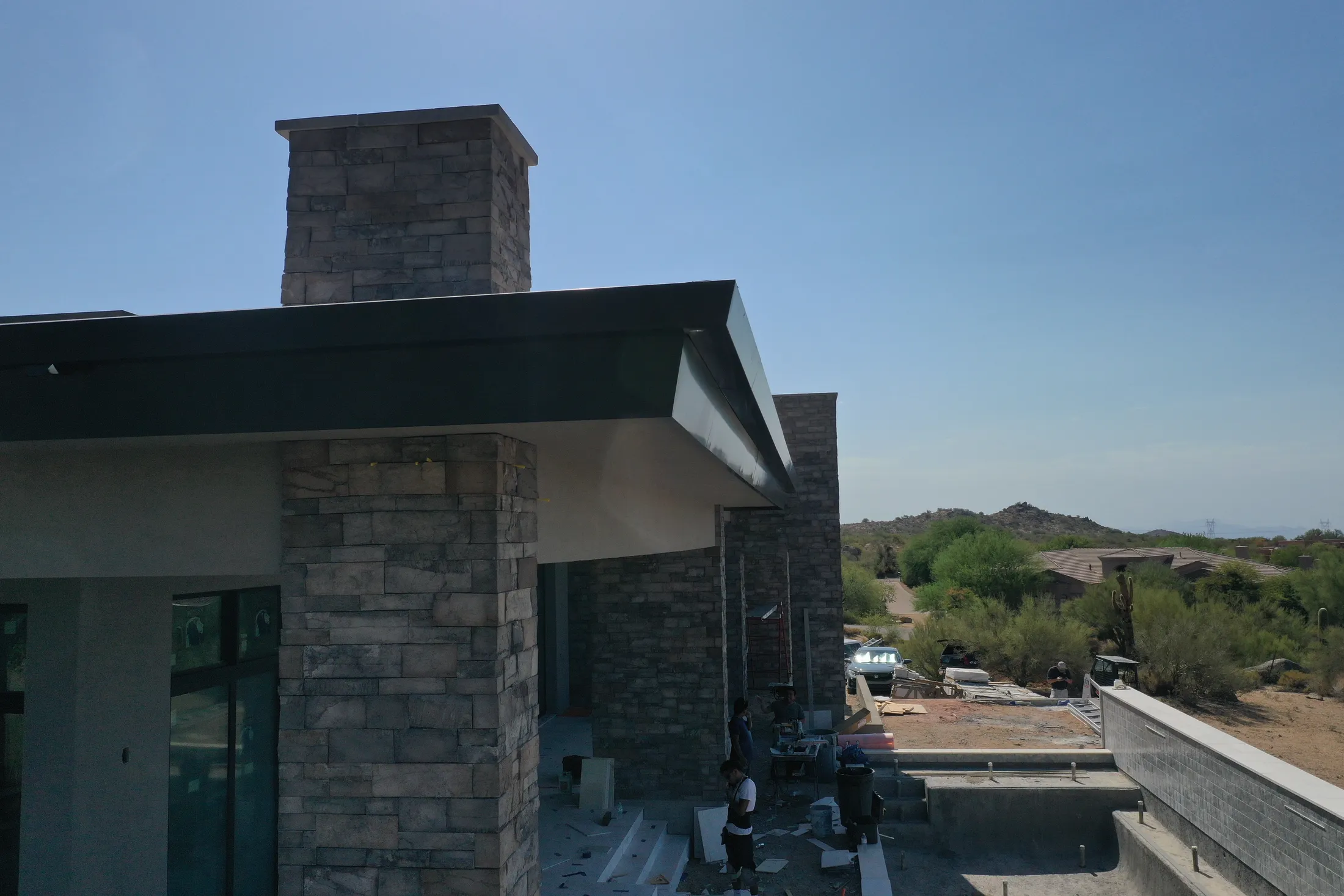 Black metal roofline and fascia over stone columns on a modern Phoenix custom home