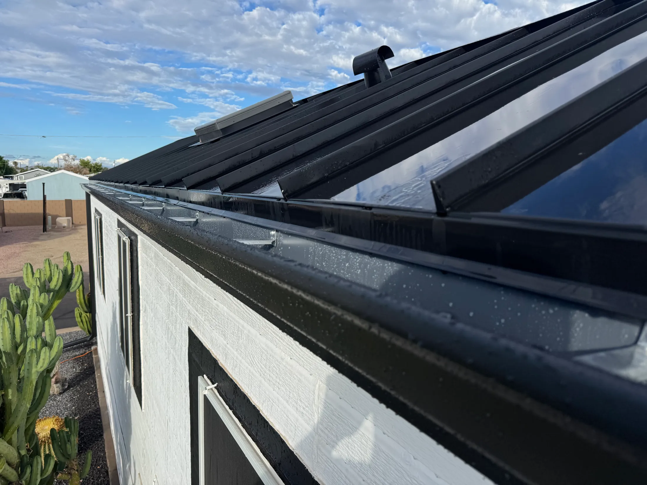 Black seamless gutter installed along a standing seam metal roof in Phoenix
