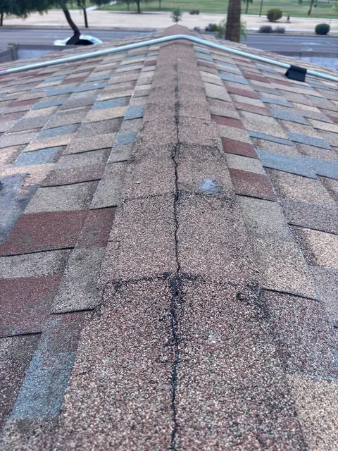 Roofer repairing wind-damaged shingles on a Phoenix home