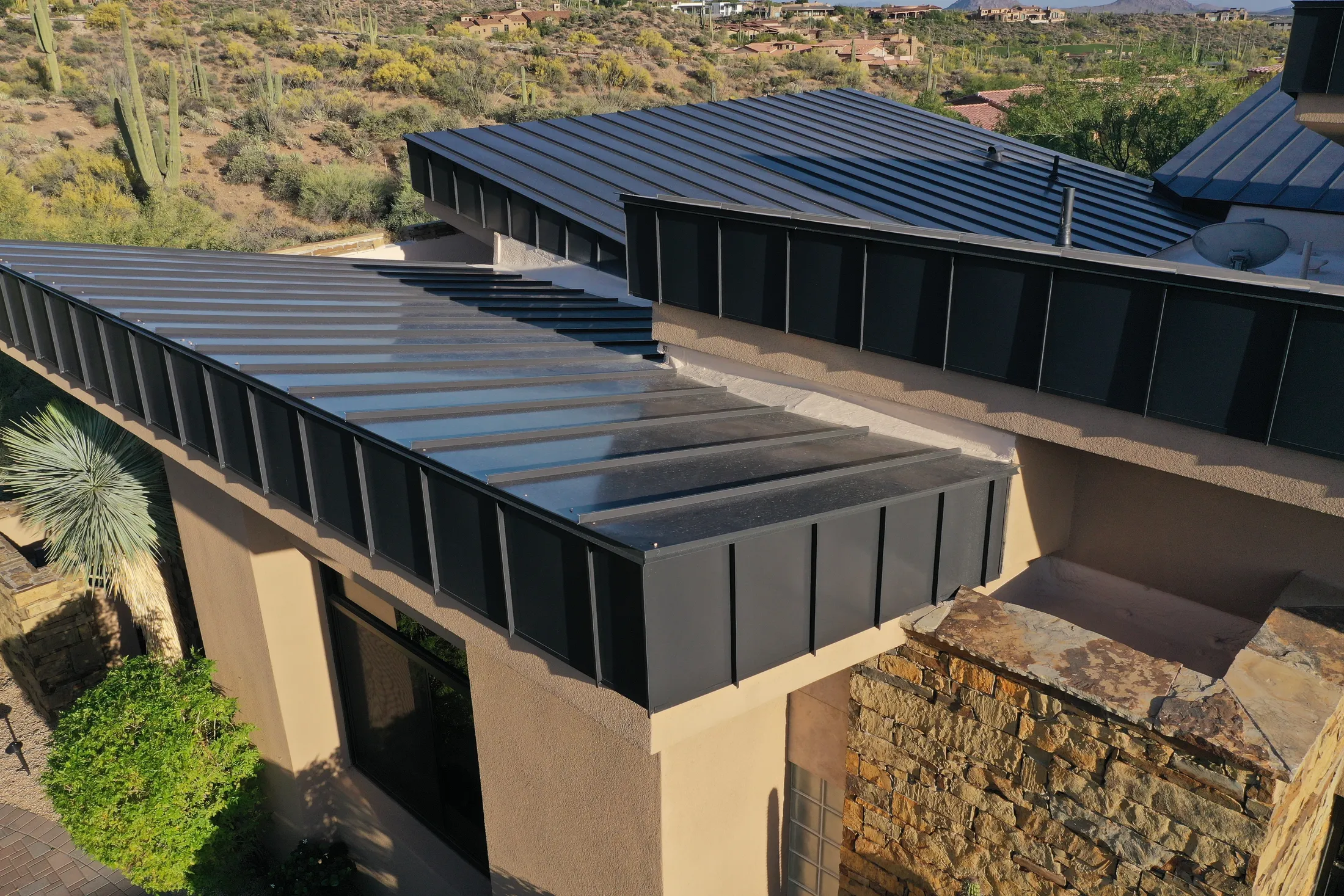 Dark standing seam metal roof on a stone and stucco custom home in the desert foothills