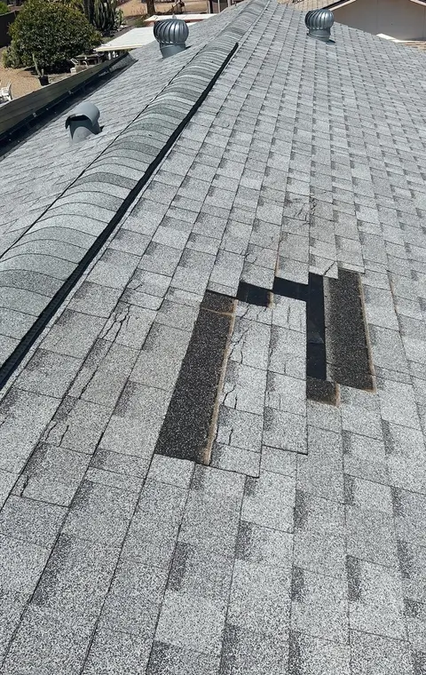 Wind-damaged shingle roof in Phoenix after a monsoon storm